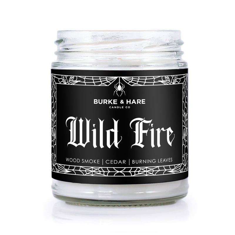 bonfire scented candle with black label that has white spiderweb border and reads 