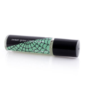 Graveyard scented perfume with a black label that features a spiderweb on half over a green background.