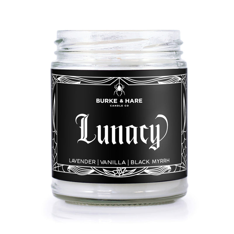Witchy inspired scented candle that has a black label with a white spiderweb border and says Lunacy in gothic font.