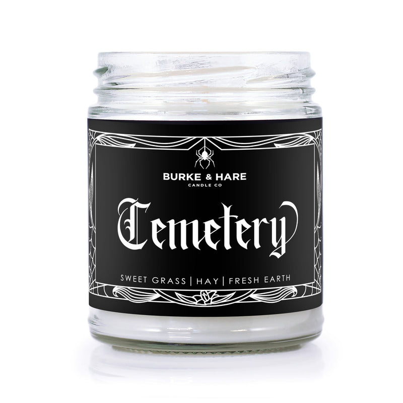Graveyard scented candle with a gothic label that has white spiderweb border and white text that reads 