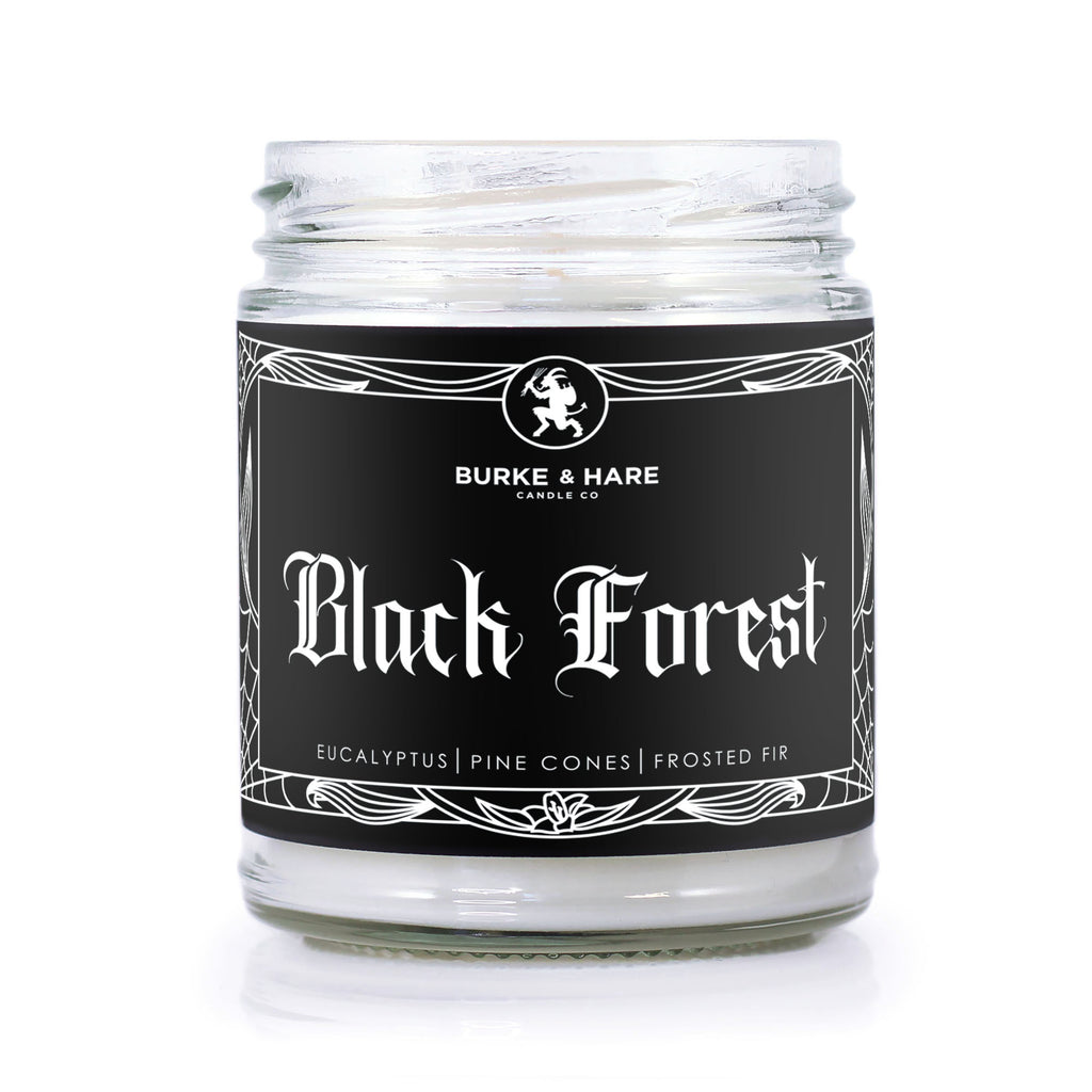 Forest scented candle with black label that has white filigree border and says "Black Forest" in white gothic font. There is an image of Krampus at the top. 