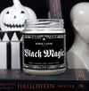 Black Magic Halloween Candle set in a spooky scene with halloween objects. Candle has a black label with spiderweb boarder 