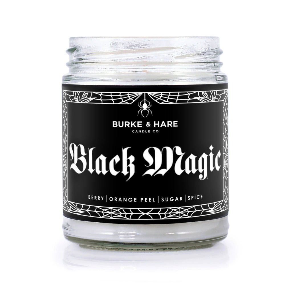 Halloween scented candle in clear jar with black label that reads Black Magic in white font
