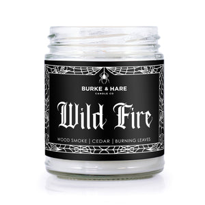 bonfire scented candle with black label that has white spiderweb border and reads "Wild Fire" in gothic font.