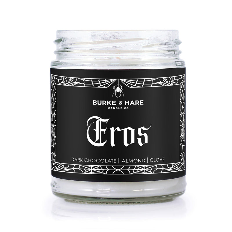 lit candle with black label and gothic spiderweb boarder that says Eros in white text.  