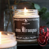 Lit krampus candle on a shelf with red christmas ribbon. Candle has a black label with filigree border and a silhouette of krampus at the top. Label says "vom krampus" in white gothic font