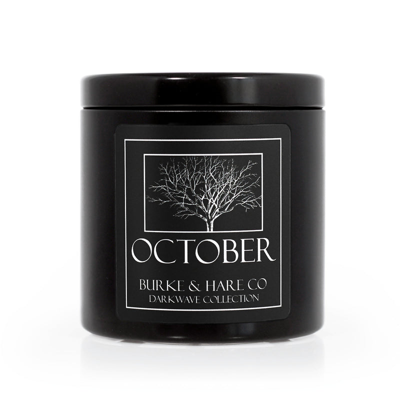 Halloween scented candle in a black tin with a black label that has a spooky skeletal tree on it and says October in white font