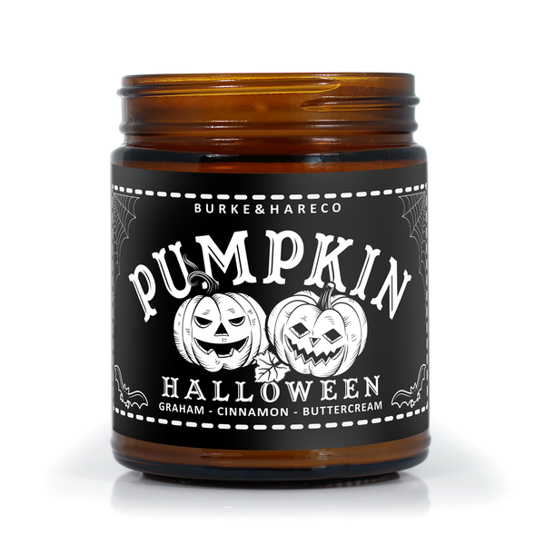 Pumpkin scented halloween candle in an amber jar with a black label featuring illustration of vintage jack o lanterns and spiderwebs