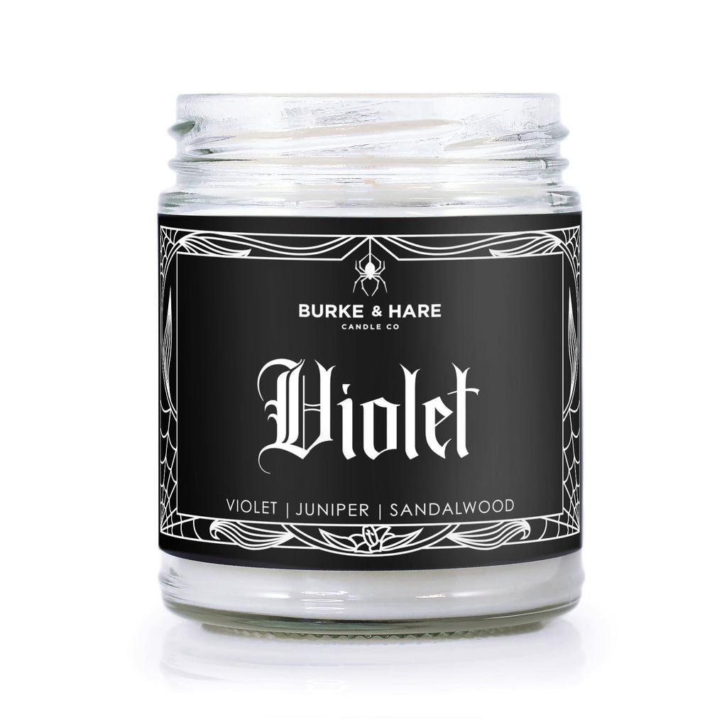 sandalwood scented candle with black label that has a spiderweb border and reads Violet in gothic font. 