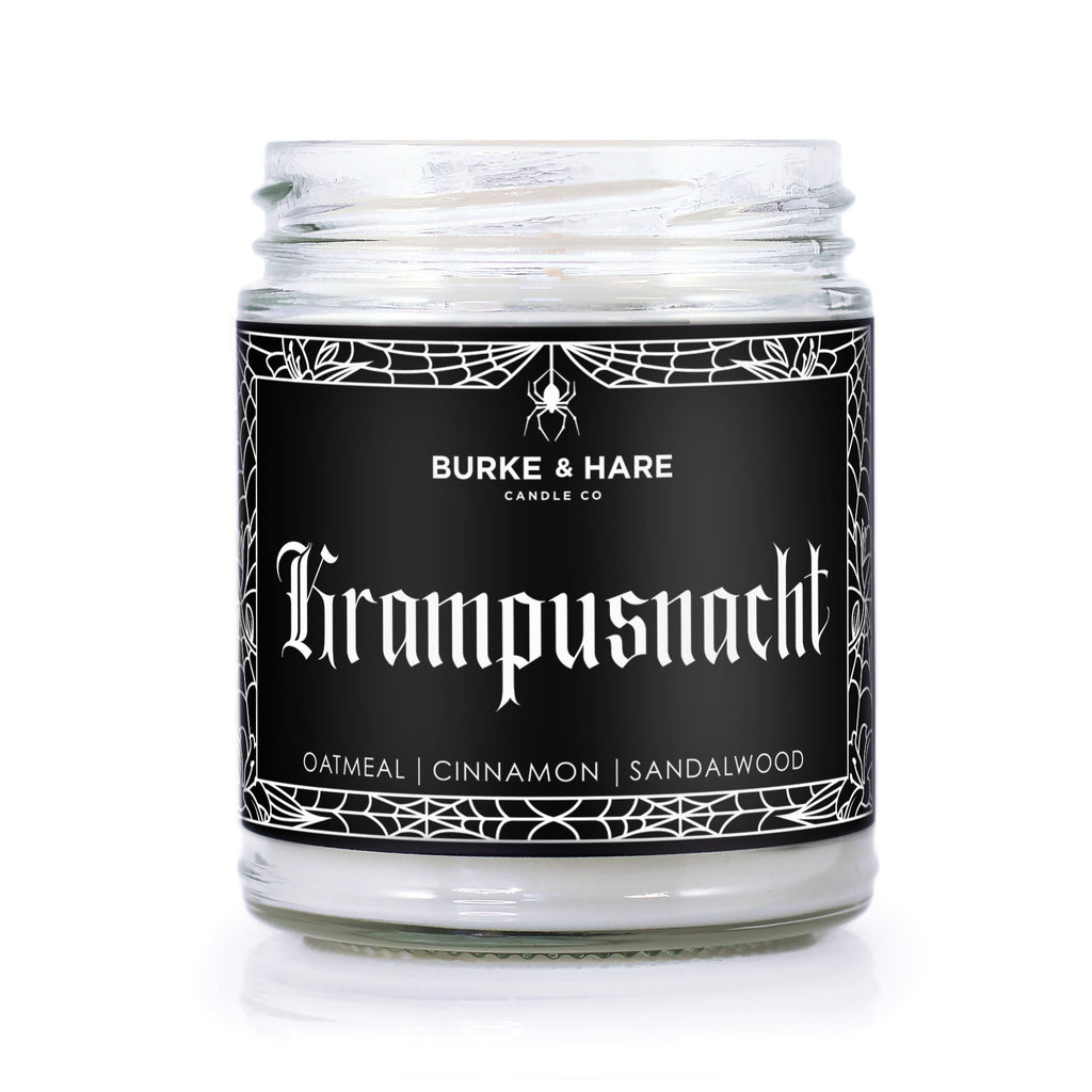 Krampus Inspired candle with a black label and gothic text that says "krampusnacht" with scent notes listed oatmeal, cinnamon and sandalwood in a clear jar.