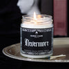 Nevermore scented candle with black label and spiderweb border lit in a gothic scene 