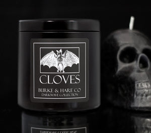 Gothic Home Decor Ideas. Black candle with a white bat on the label in a black moody scene with a skull in the background.
