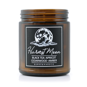 Scented candle for fall with black label featuring a harvest moon