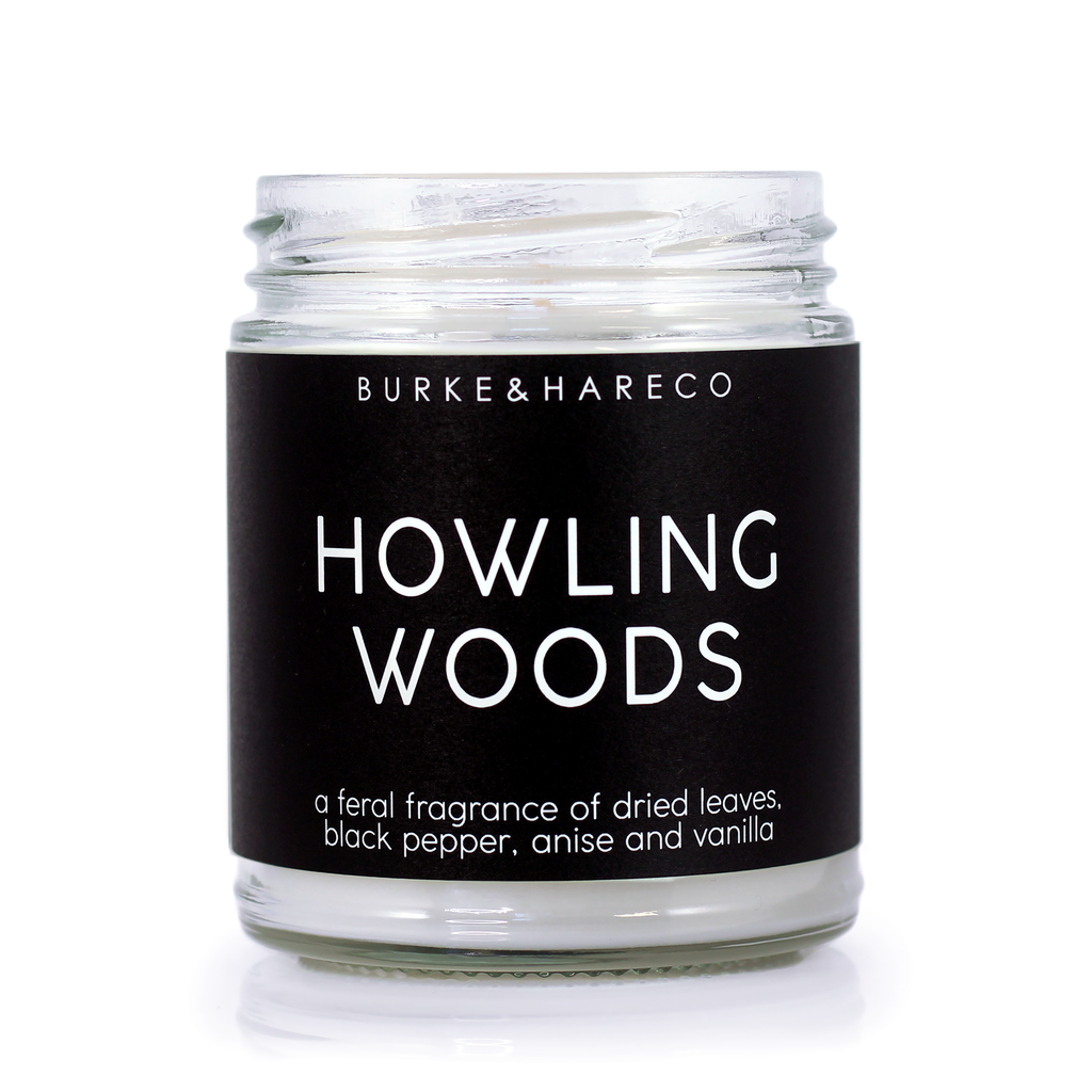werewolf halloween candle with a black label and white text that says Howling Woods