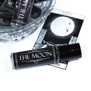 tarot perfume in a 8ml roll on vial with a black label and white text that says "the moon" against a tarot card background
